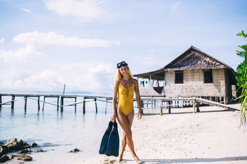 Young blonde in goggles carrying flippers on beach © BullRun