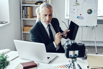Fototapeta na wymiar Senior man in elegant business suit using digital tablet while making social media video