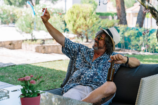 Adult man in a garden making a selfie and with a beer in his hand