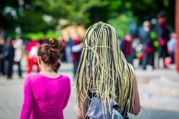 Fototapeta na wymiar hair on the braids of a girl on the street. blond long hair braided in street photography.