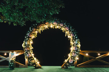 night wedding ceremony. The wedding is decorated with an arch in the evening. a garland of light...