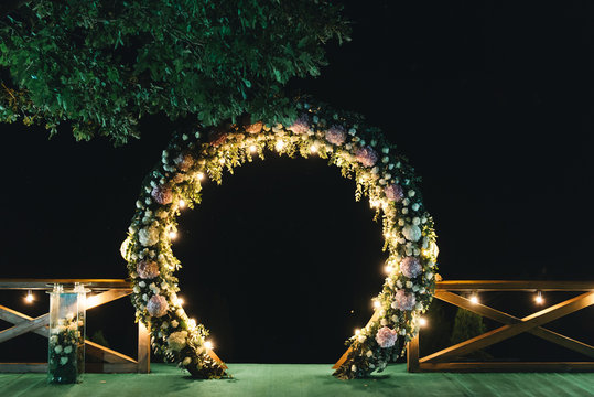 night wedding ceremony. The wedding is decorated with an arch in the evening. a garland of light bulbs.