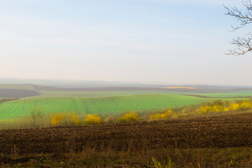 Plowed land and autumn green hills with outgoing horizon.