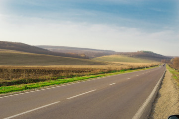 Freeway with cars in the countryside among the hills in the fall.