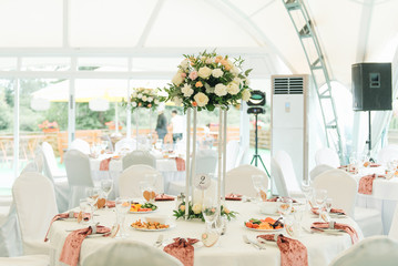 View of the wedding hall, the tent, wedding tables decorated with fresh flowers