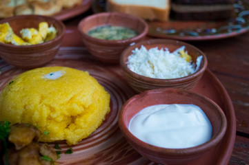 Mamalyga, sour cream, feta cheese, meat, sauce and egg on a plate in the national style.