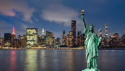 statue of liberty in front of Manhattan skyline at night - obrazy, fototapety, plakaty