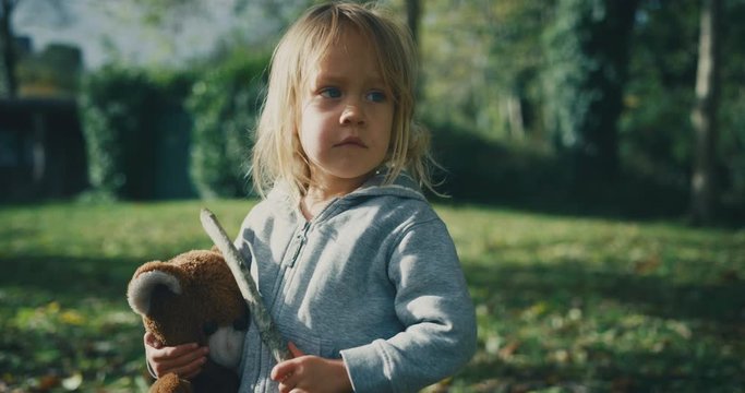 Little toddler standing in the woods with a teddybear