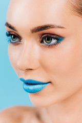 close up view of beautiful woman with blue makeup isolated on blue