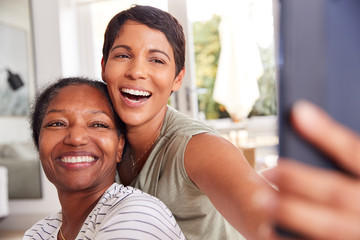 Mother With Adult Daughter Taking Selfie At Home Together