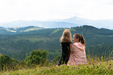 Woman and child girl having fun with mountain view behind