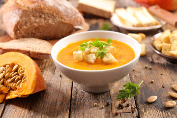 pumpkin soup in bowl with crouton on wood background