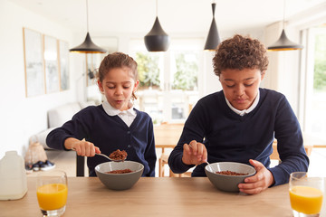 Children At Kitchen Counter Eating Sugary Breakfast Before Going To School