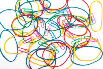 Colored rubber bands for money and multi-colored paper clips on a white background