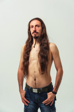 A Man With Long Hair And A Beard With A Naked Torso On A White Background. Long Flowing Hair Of A Young Boy. Care For Long Men's Hair