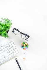 Office creative desk with supplies and coffee cup. White office table with keyboard, blank notebook, glasses, supplies and coffee cup. Flatlay layout copy space top view