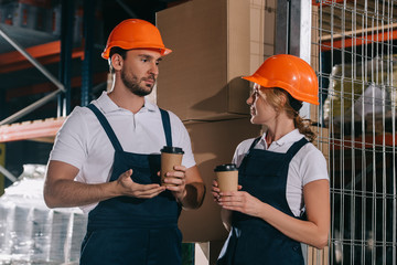 two warehouse workers talking while holding coffee to go