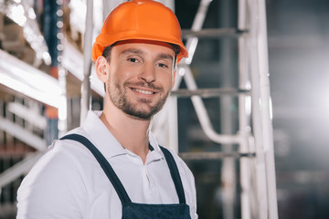 Handsome warehouse worker in helmet smiling at camera