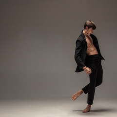 Man in casual office style clothes moving and dancing isolated on grey background. Art, motion,...