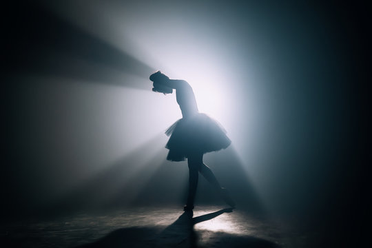 Fototapeta Silhouette of ballerina who has finished dancing her part in performance on stage. Distressed woman bowed her head. Stress, problems concept.