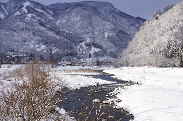 Fototapeta na wymiar 雪国、魚野川の流れと雪景色
