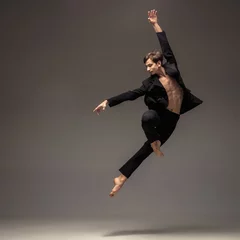 Fotobehang Man in casual office style clothes jumping and dancing isolated on grey background. Art, motion, action, flexibility, inspiration concept. Flexible caucasian ballet dancer, weightless jumps. © master1305