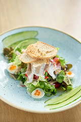Olivier salad with Lamb tongue, salted cucumber, quail egg. Wooden table background. Menu restaurant. Russian traditional salad