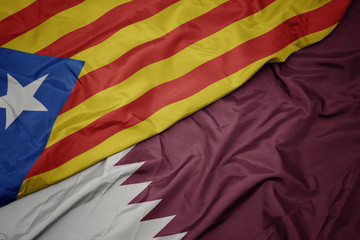 waving colorful flag of qatar and national flag of catalonia.