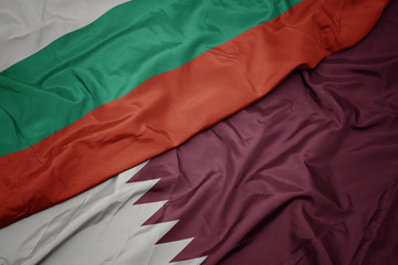 waving colorful flag of qatar and national flag of bulgaria.