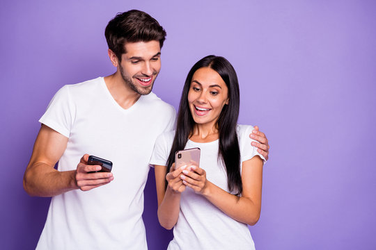 Close-up portrait of his he her she nice attractive lovely cheerful cheery glad amazed couple using digital device watching media content isolated on purple violet lilac color pastel background