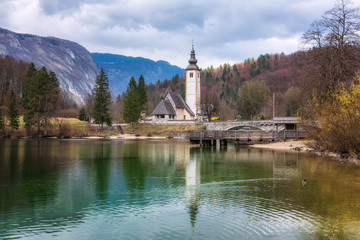 Panoramic spring view of Bohinj lake with the church of St John the Baptist and the stone bridge in Triglav National Park, located in Julian Alps, Slovenia.