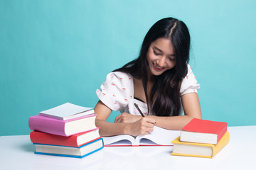 Young Asian woman read a book with books on table.