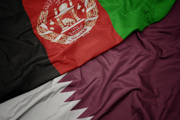 waving colorful flag of qatar and national flag of afghanistan.