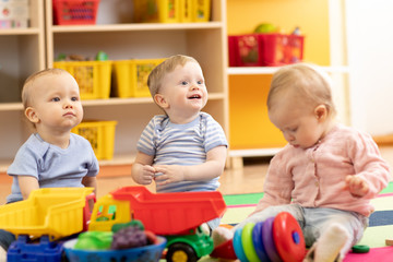 Obraz premium Little toddlers boys and a girl playing together in kindergarten or creche. Preschool children in day care centre