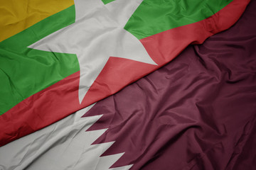 waving colorful flag of qatar and national flag of myanmar.