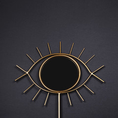 An eye-shaped mirror with a round pupil as a detail for a Scandinavian modern interior on a dark background.