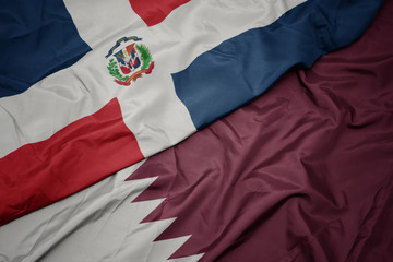 waving colorful flag of qatar and national flag of dominican republic.