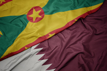 waving colorful flag of qatar and national flag of grenada.