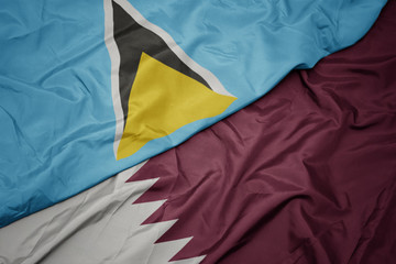 waving colorful flag of qatar and national flag of saint lucia.
