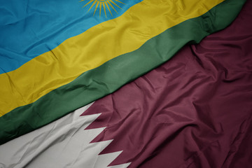 waving colorful flag of qatar and national flag of rwanda.