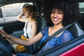 Two young women friends driving in the city - Millennials use the car to get around