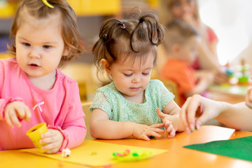 Little kids having fun together with colorful modeling clay at daycare. Children playing with plasticine or dough.