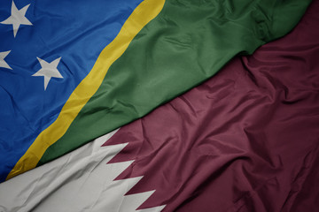 waving colorful flag of qatar and national flag of Solomon Islands .