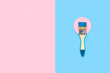 Renovation concept. Blue-pink background with paint brush on a pink circle. Flat lay, top view, copy space.
