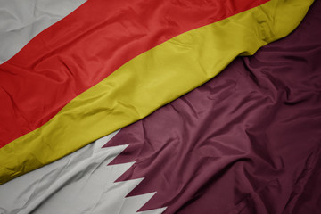 waving colorful flag of qatar and national flag of south ossetia.