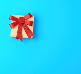 closed brown gift box with a red shiny bow on a blue background