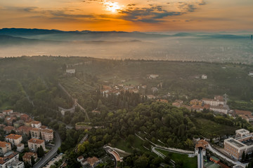Aerial drone shot view of sunrise on foggy Veronetta colline with Castel San Pietro and funicolare