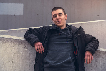 portrait of a smiling young man leaning against a concrete wall