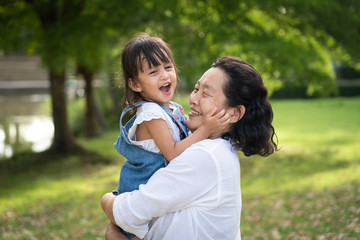 Adorable asian granddaughter is playing and laughing together with grandmother with fully happiness moment in the green park, concept of love and relation of difference generation in family lifestyle