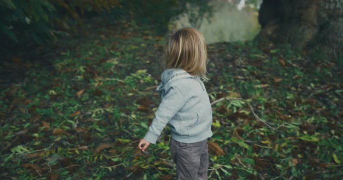 Little toddler playing with a stick in the woods